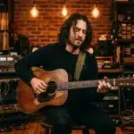Homme jouant guitare acoustique dans studio professionnel