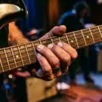 Main de musicien sur le manche d'une guitare électrique